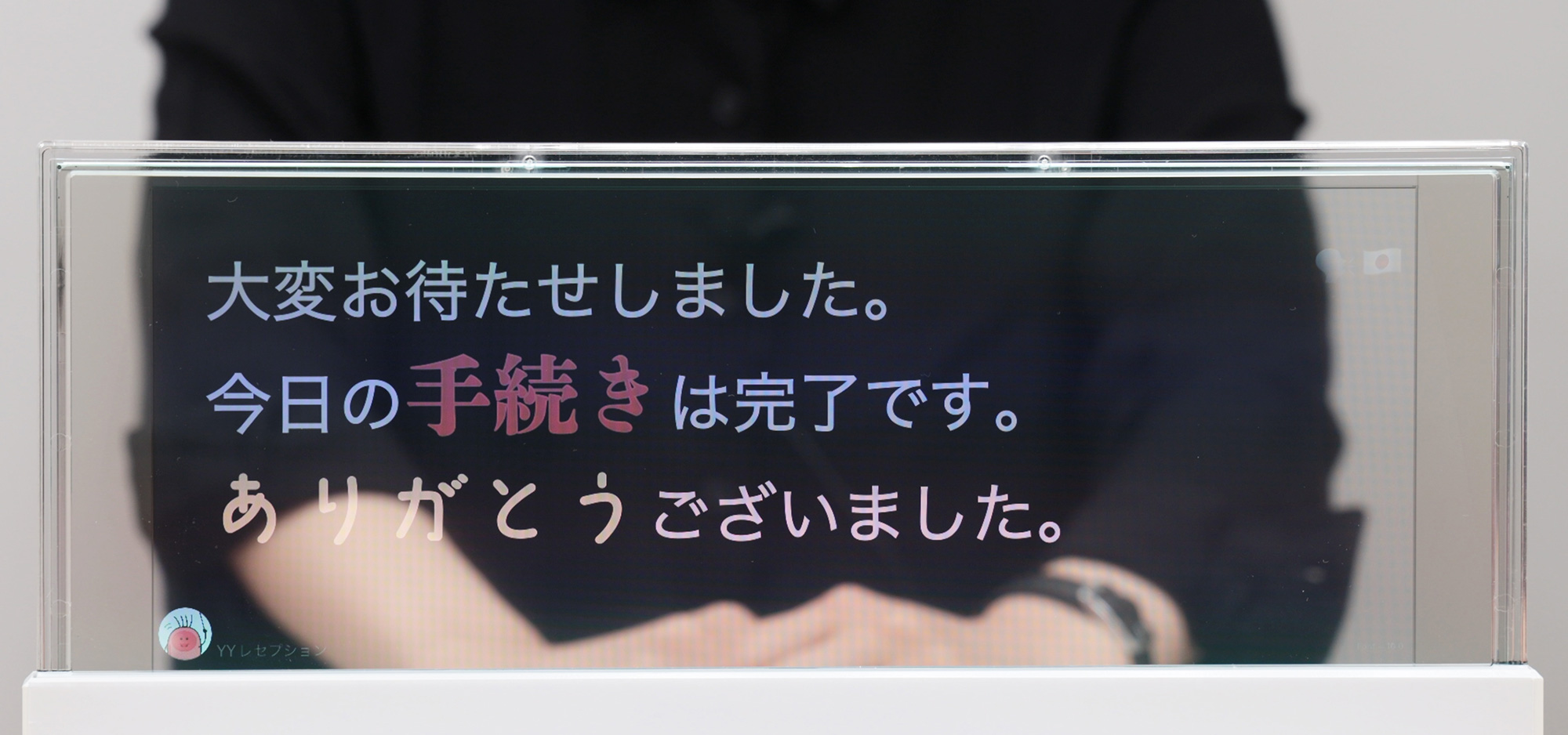 DNP対話支援システムの画面。透明な液晶ディスプレイに話した内容が表示され、「ありがとう」の文字は優しい印象のフォントで表示されている。